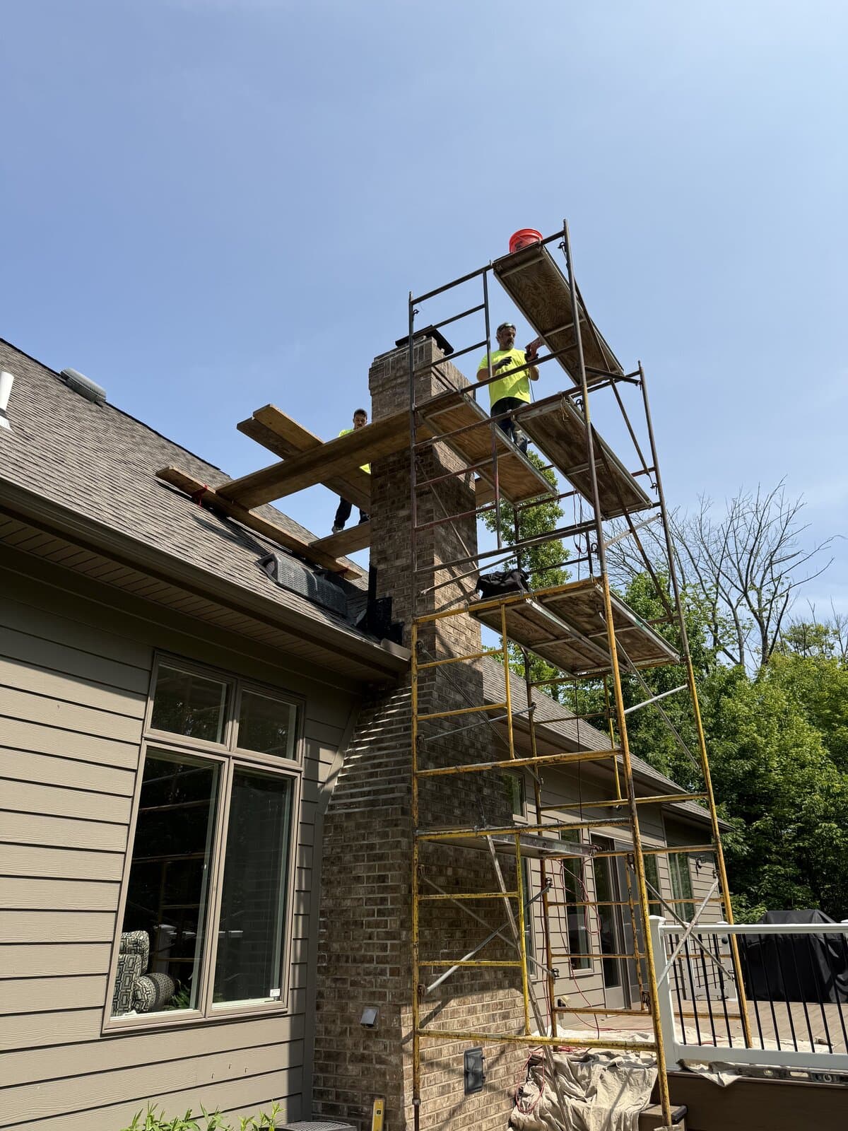 Crew on scaffolding repairing a brick chimney
